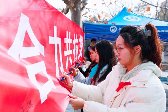 20231127中國石油大學(xué)（華東）青年學(xué)子在合力共抗艾滋的條幅上簽字，表達(dá)抗擊艾滋病的決心和信心  .jpg